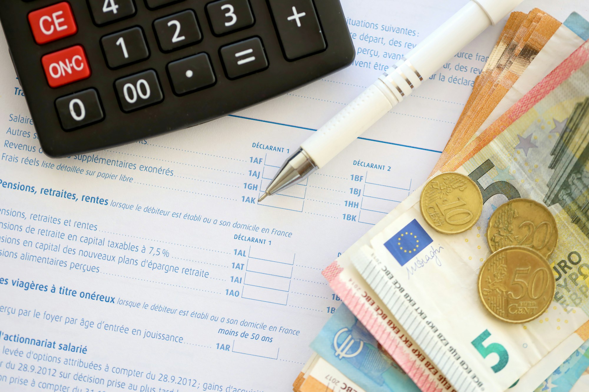 Filling french tax form process with calculator, pen and euro money bills close up